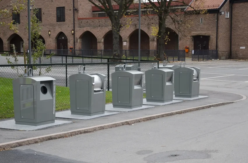 Contêineres cinza para coleta seletiva instalados em calçada